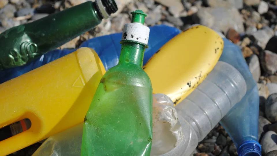 Plastflaskor i olika färger på en strand. Foto: Pixabay.