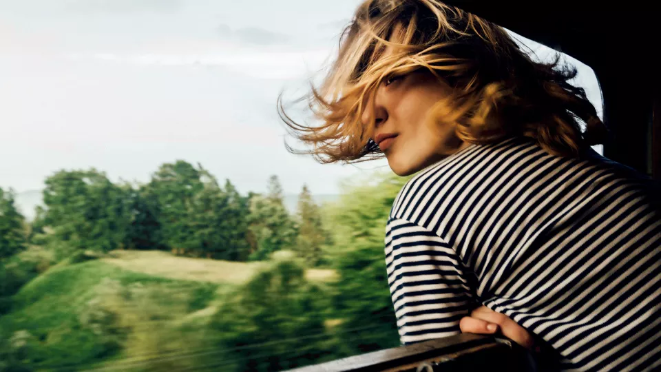 Kvinna på tåg ser ut över landskap.