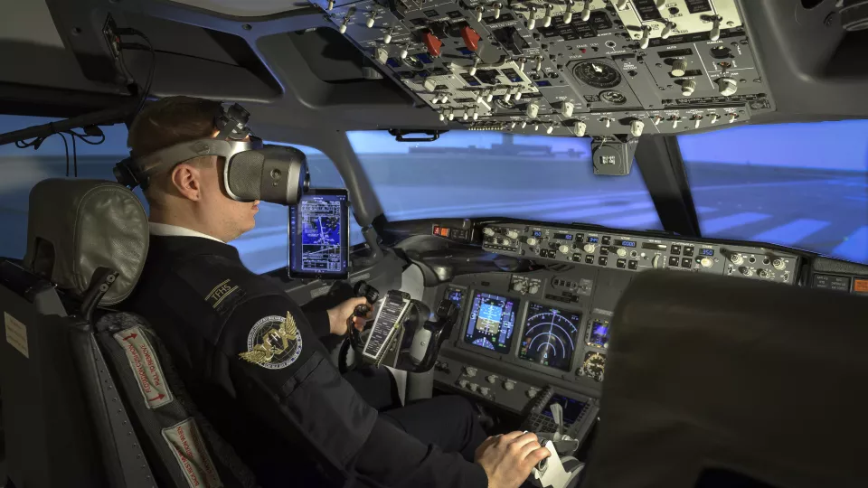 Flygpilot i cockpit med VR-glasögon. Foto. 