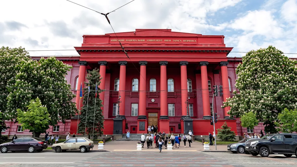 Röd universitetsbyggnad med pelare framför entrén. Foto
