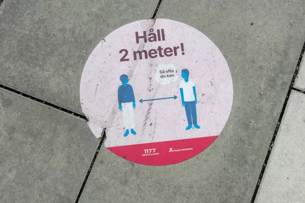 Bild på en skylt som säger att man ska hålla två meter avstånd till varandra