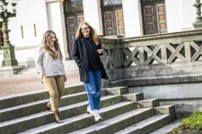 Två kvinnor går nedför en trappa framför Lunds universitets huvudbyggnad.