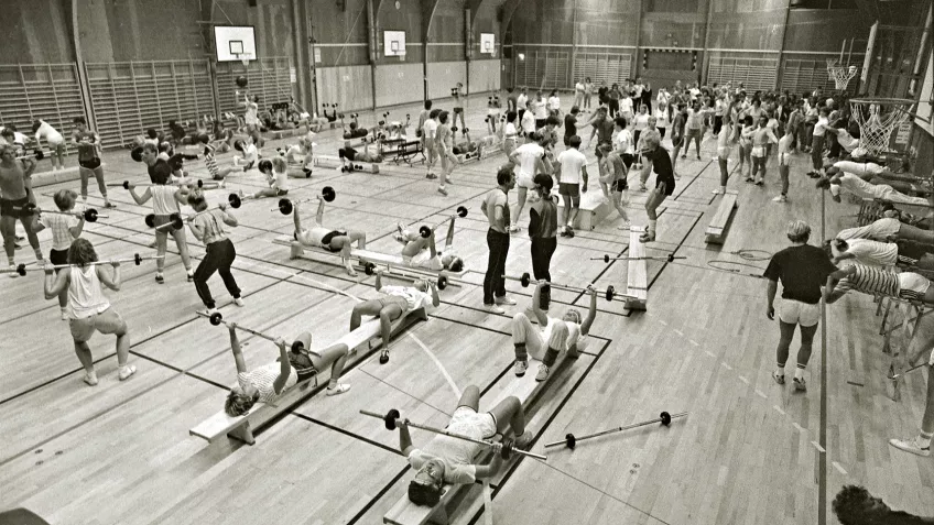 Svartvitt foto taget 1984 från en av Gerdahallens stora gympasalar där mängder av människor motionerar.