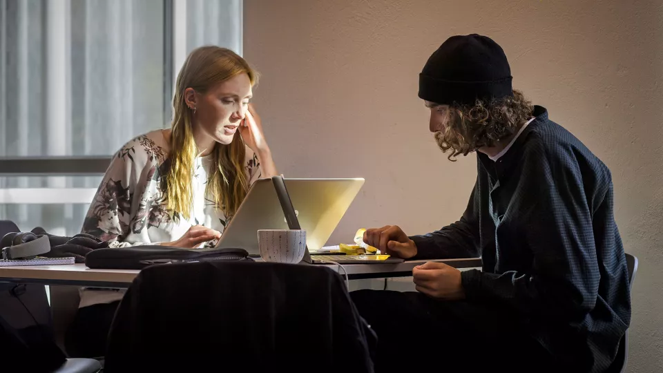 Två studenter pluggar vid ett bord.