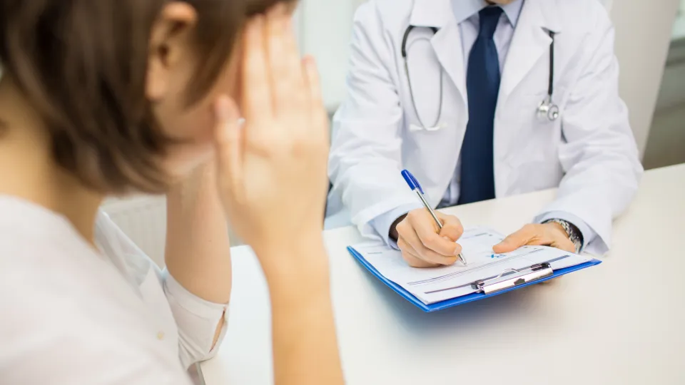 Kvinna och doktor vid bord.