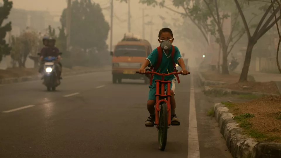 Pojke som cyklar genom avgaser på väg till skolan. Foto: Aulia Erlangga.