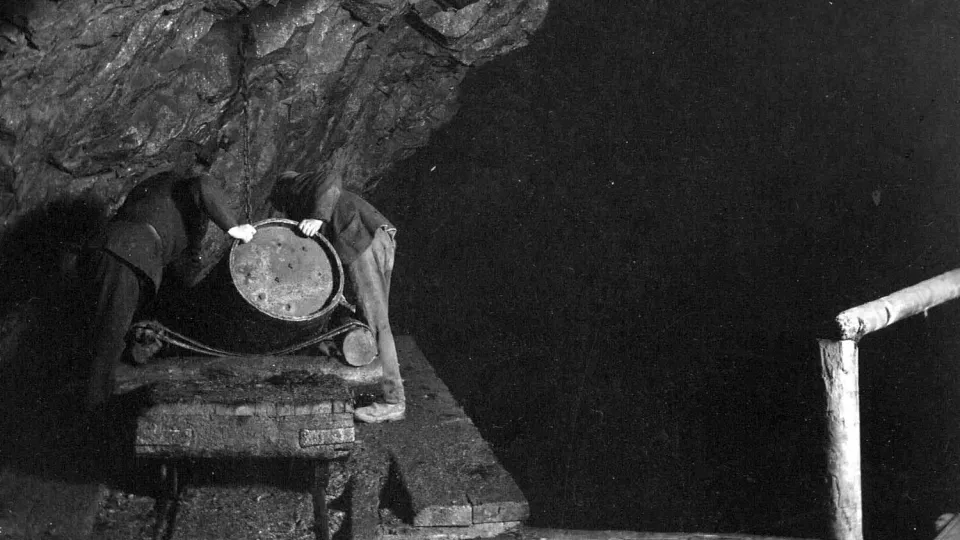 Två personer i en mörk gammal gruva. Historisk bild.