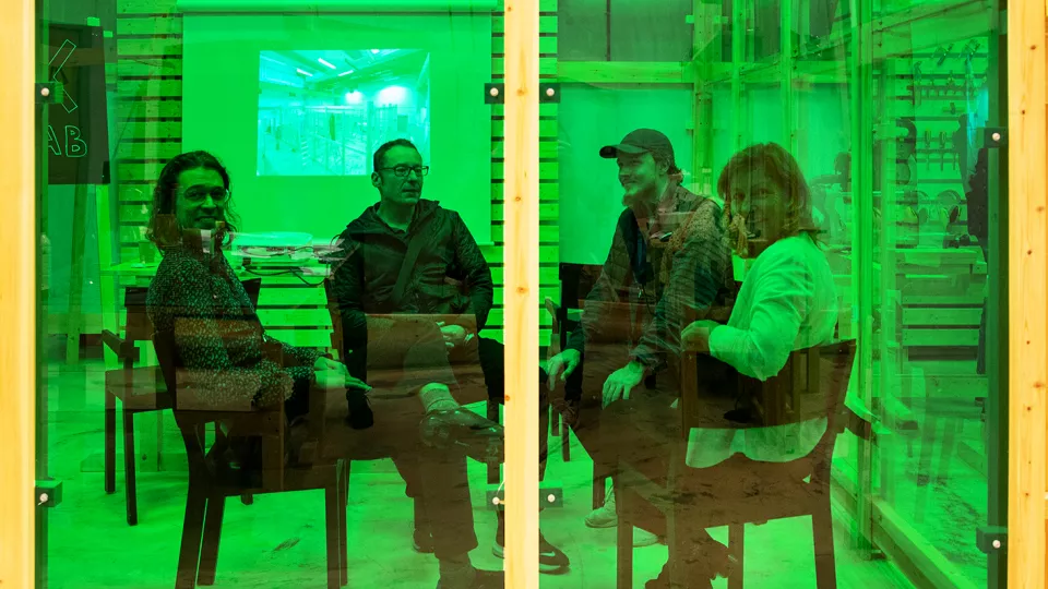 Personer som sitter bakom ett grönt glas
