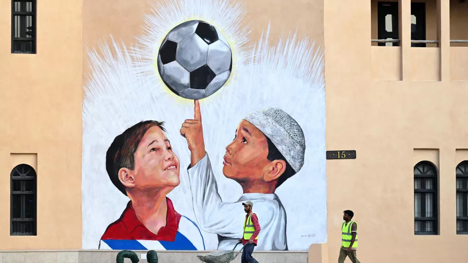 Foton som visar en målning av en fotboll och två pojkar framför byggarbetare.