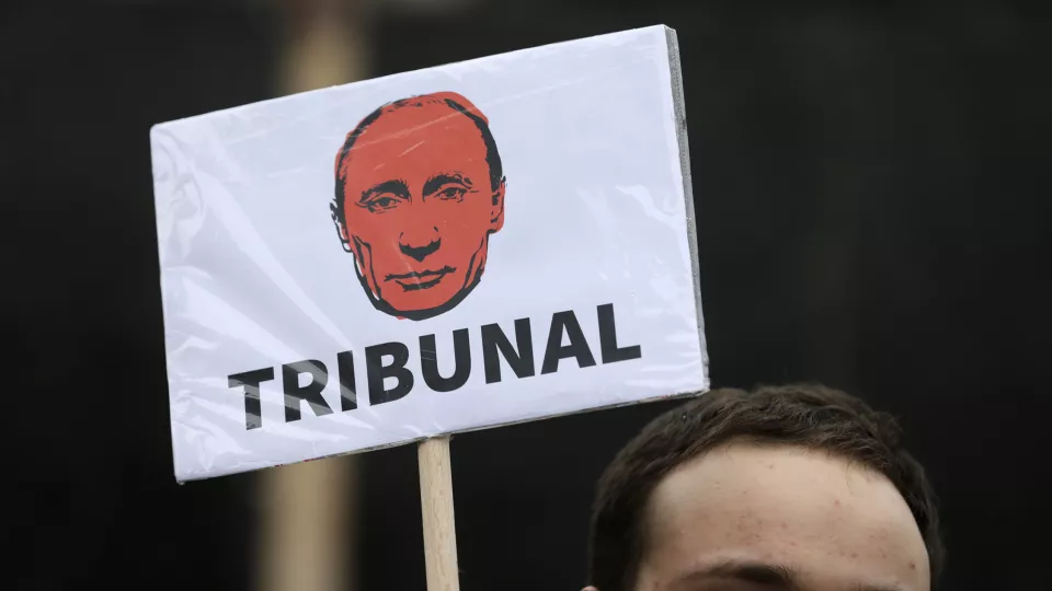 Demonstrant håller ett plakat som föreställer Rysslands president Vladimir Putin med texten tribunal. Foto: Andrej Cukic/EPA.