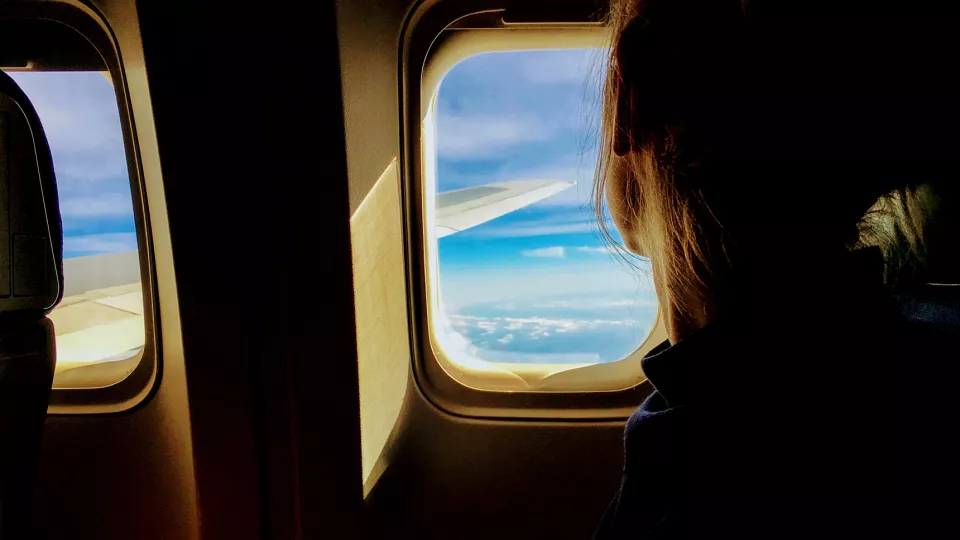 Kvinna tittar ut genom flygplansfönster. 