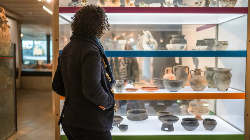 Man framför monter på museum med gamla krukor
