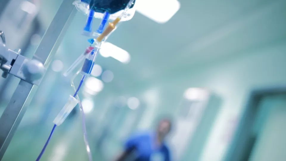 Intravenös dropp med vätska redo att använda, i bakgrunden läkare, fotografi. Foto: iStock/sudok1