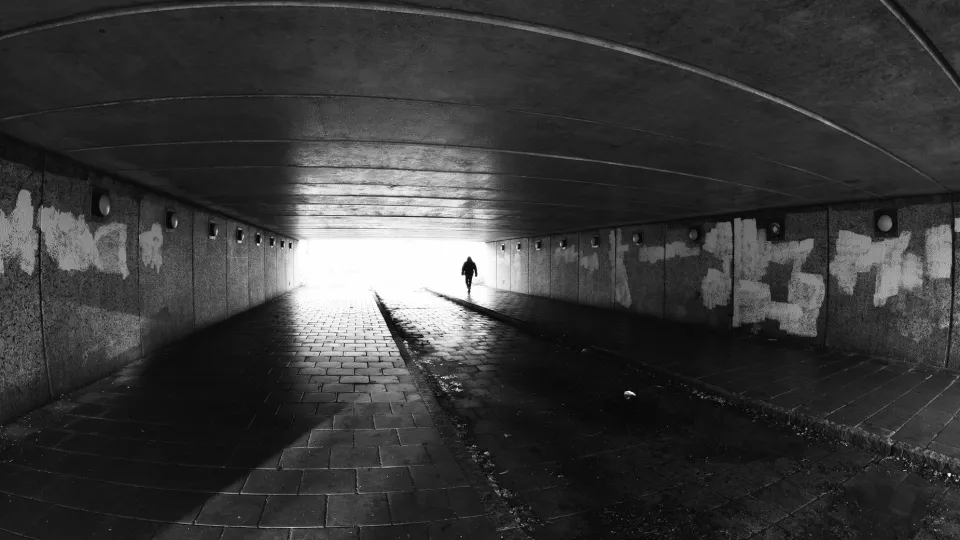 Svartvitt fotografi av tunnel med grafitti. I ljuset av slutet av tunneln ser man konturerna av en man, fotografi. Foto: iStock