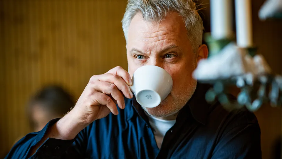 Joakim Zander dricker ur en kaffemugg. 
