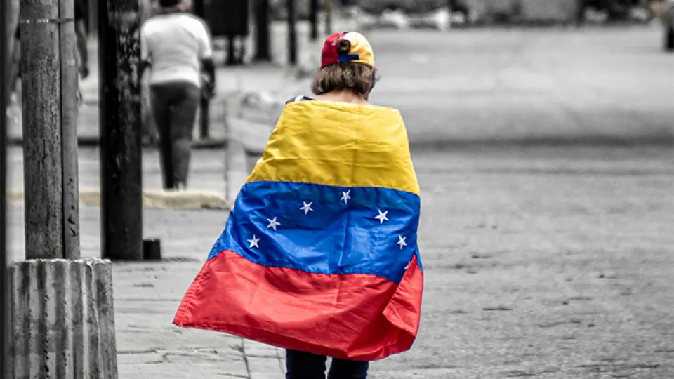 Person seen from the back, draped with a Venezuelan flag.