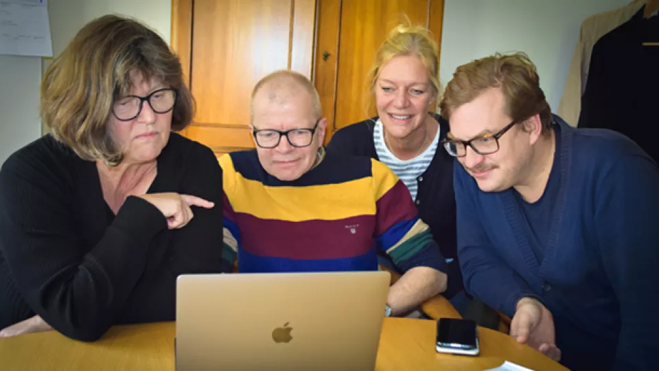 Fyra personer tittar på en laptop.