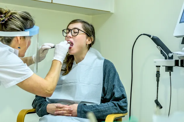 Logoped undersöker person som gapar.