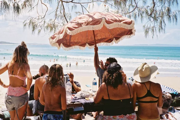Personer solbadar på en strand.