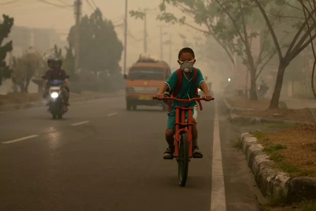 Pojke som cyklar genom avgaser på väg till skolan. Foto: Aulia Erlangga.