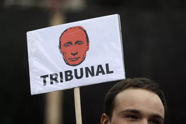 Demonstrant håller ett plakat som föreställer Rysslands president Vladimir Putin med texten tribunal. Foto: Andrej Cukic/EPA.
