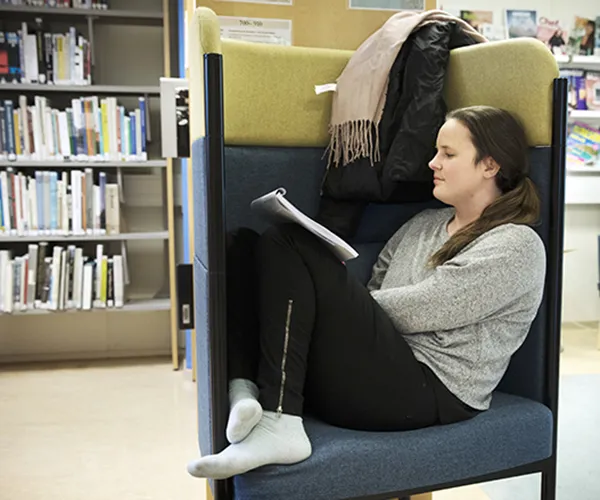 Student sitter i fåtölj med benen uppe och läser. Foto: Johan Bävman