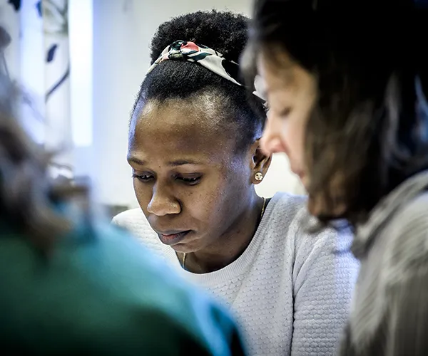 Närbild på sittande student som tittat ner med andra studenter runt om. Foto: Kennet Rouna.