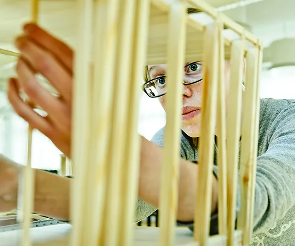 Student bygger en modell med träpinnar.