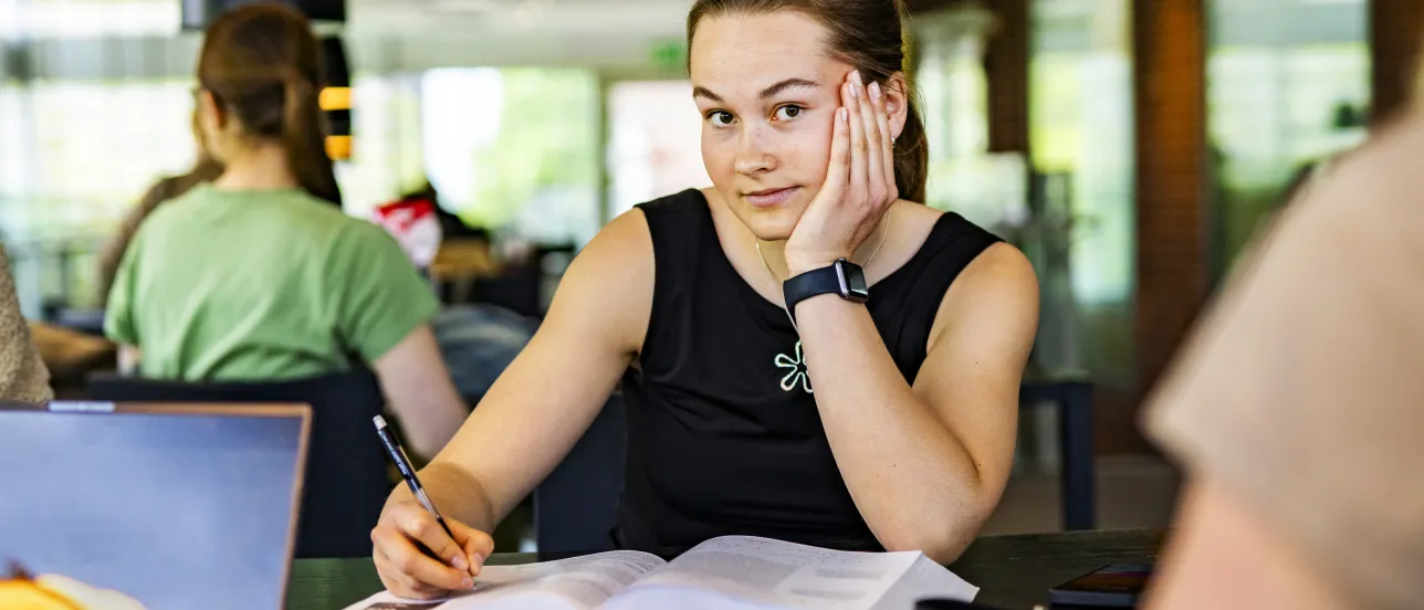 Student i studiemiljö tittar in i kameran.