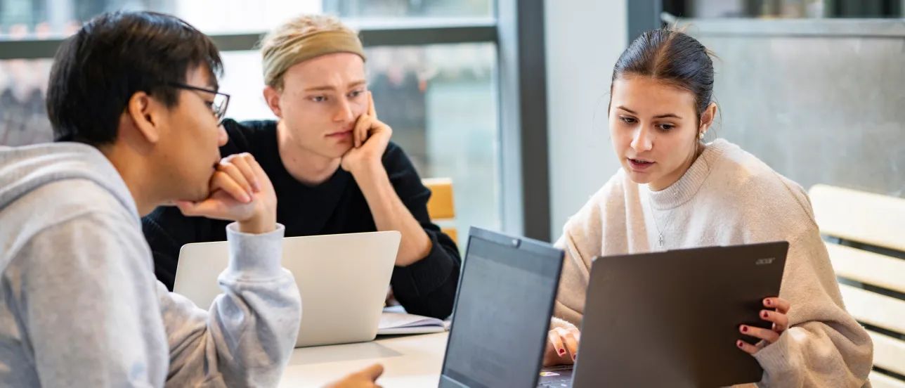 En student visar två andra studenter något på sin dator.