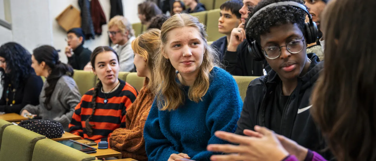 Studenter i samtal i föreläsningssal.