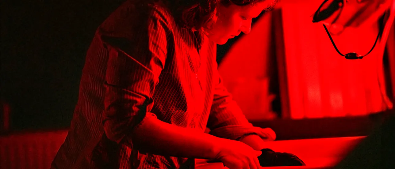 Kvinnlig student framkallar bilder i ett mörkerrum. Foto.