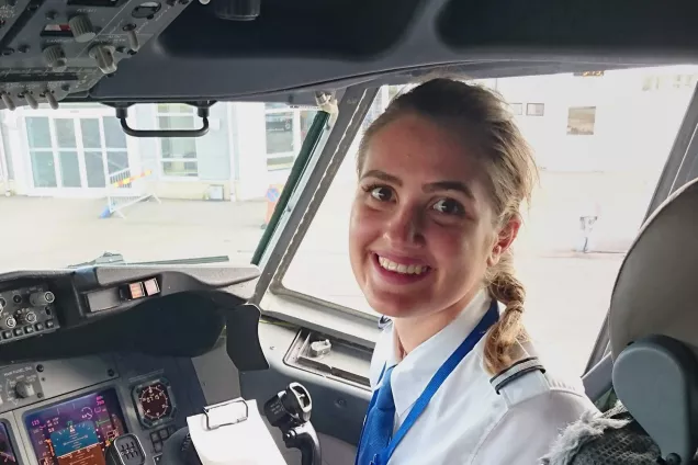 Sarah inne i cockpiten på ett flygplan, vid spakarna. Foto.