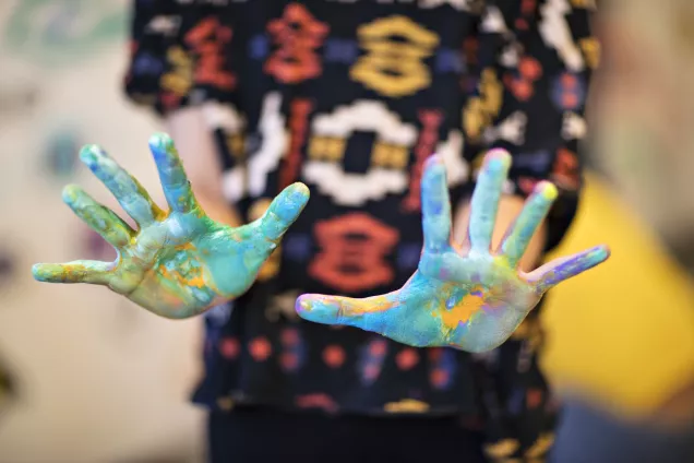 Barnhänder, kladdiga i glada färger. Foto.