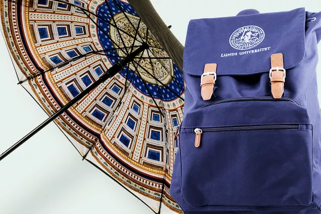 Paraply och ryggsäck med universitetsmotiv och logotyp. Foto.