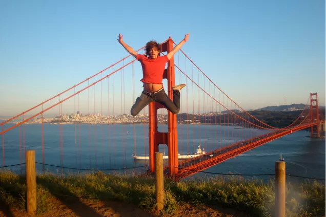 Student tar glädjeskutt framför Golden Gate. Foto. 