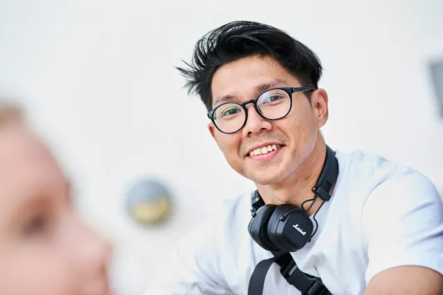 En glad student med glasögon och hörlurar. Foto Johan Persson.