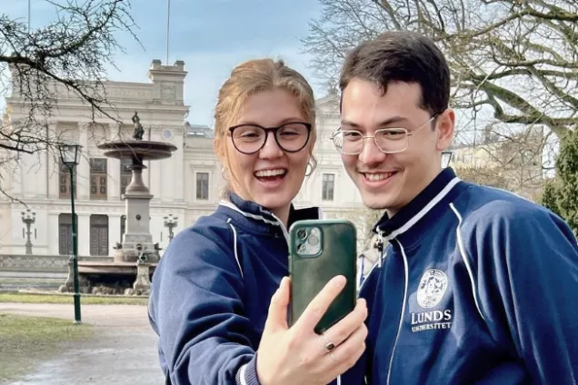 Två studenter tar selfie vid universitetshuset. Foto.