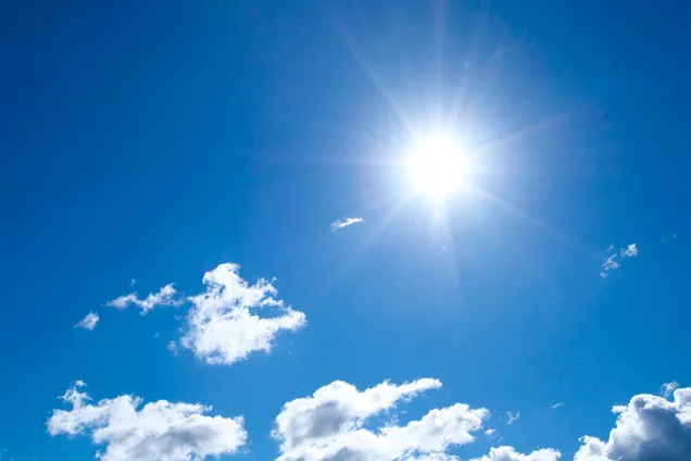 Blå himmel med sol och vita moln. Foto.