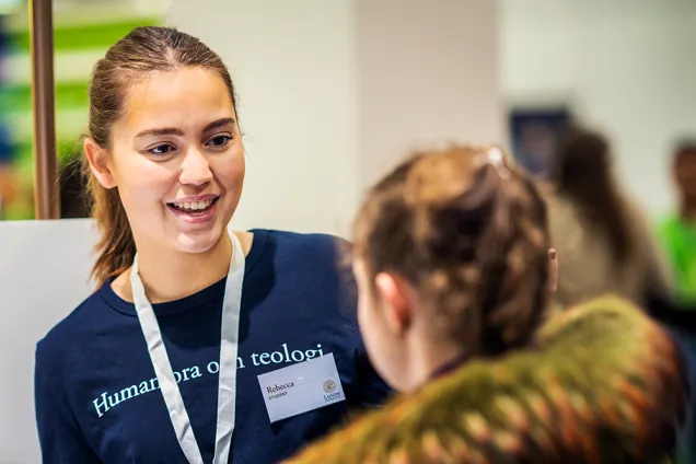 Studentambassadör samtalar med mässbesökare. Foto.