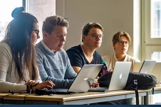 Fyra studenter med laptops på föreläsning. Foto.