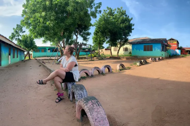 Kvinna sitter på ett staket av däck. Foto.