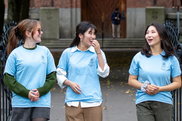 Tre glada studentskor i blå t-shirts. Foto.