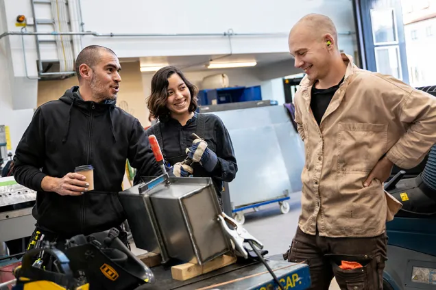Tre konsthögskolestudenter i verkstad. Foto.