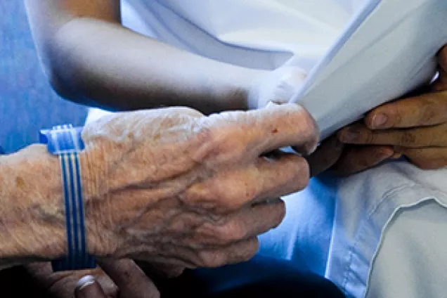En sjuksköterska och en äldre patient håller i ett pappershäfte