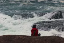 Foto av kvinna som blickar ut över stormigt hav.