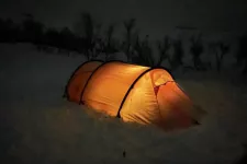 Tent illuminated from the inside in a snowy landscape. Photo.
