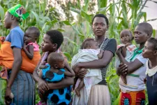 Foto. Flera kvinnor i Uganda står står uppradade tillsammans med sina barn som de bär i famnen eller på ryggen.