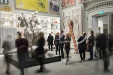Människor i oskärpa i Svenska salen på Skissernas Museum. Konst på väggarna och stora skulpturer. 
