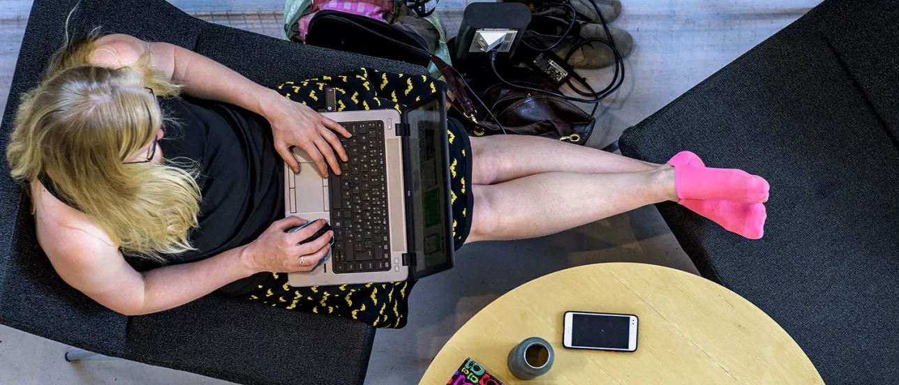 Studentska pluggar med laptop i knät. Foto.